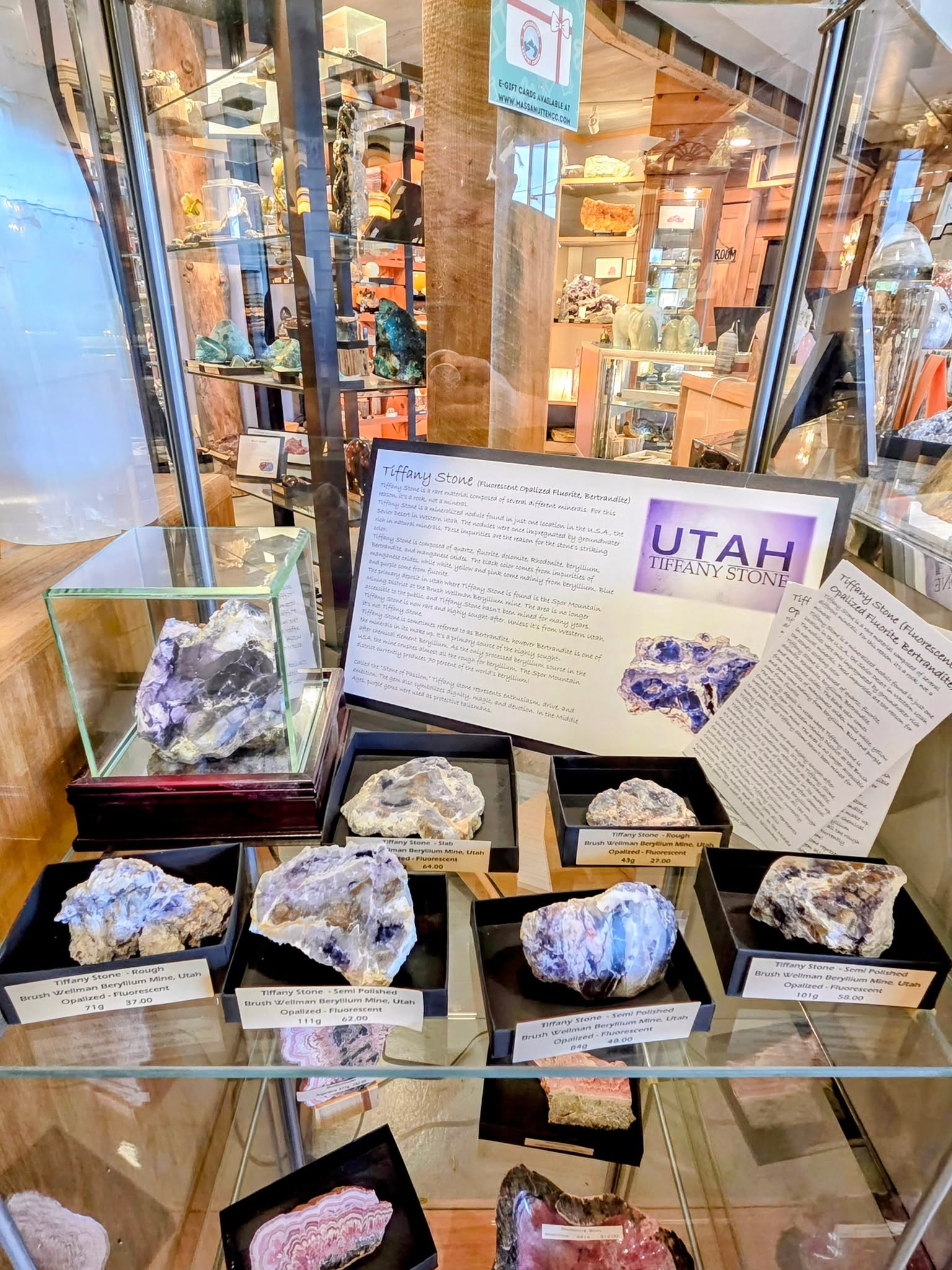 Display case with various rough and polished Tiffany Stone specimens from Utah with descriptive signs.