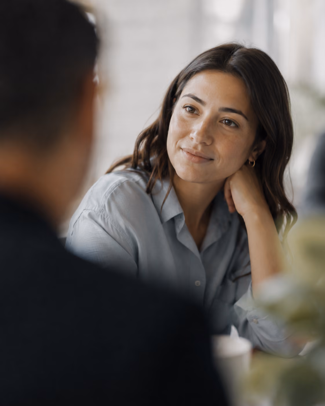 Woman attentively listening to a man during a conversation in a softly lit indoor setting.