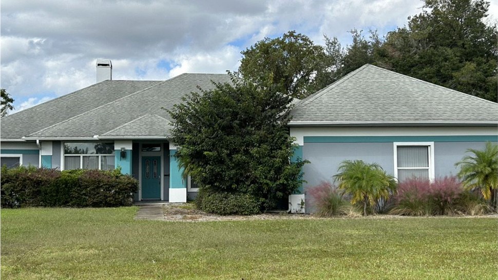 Weathered roof and overgrown landscaping before replacement on a Clermont, Florida home