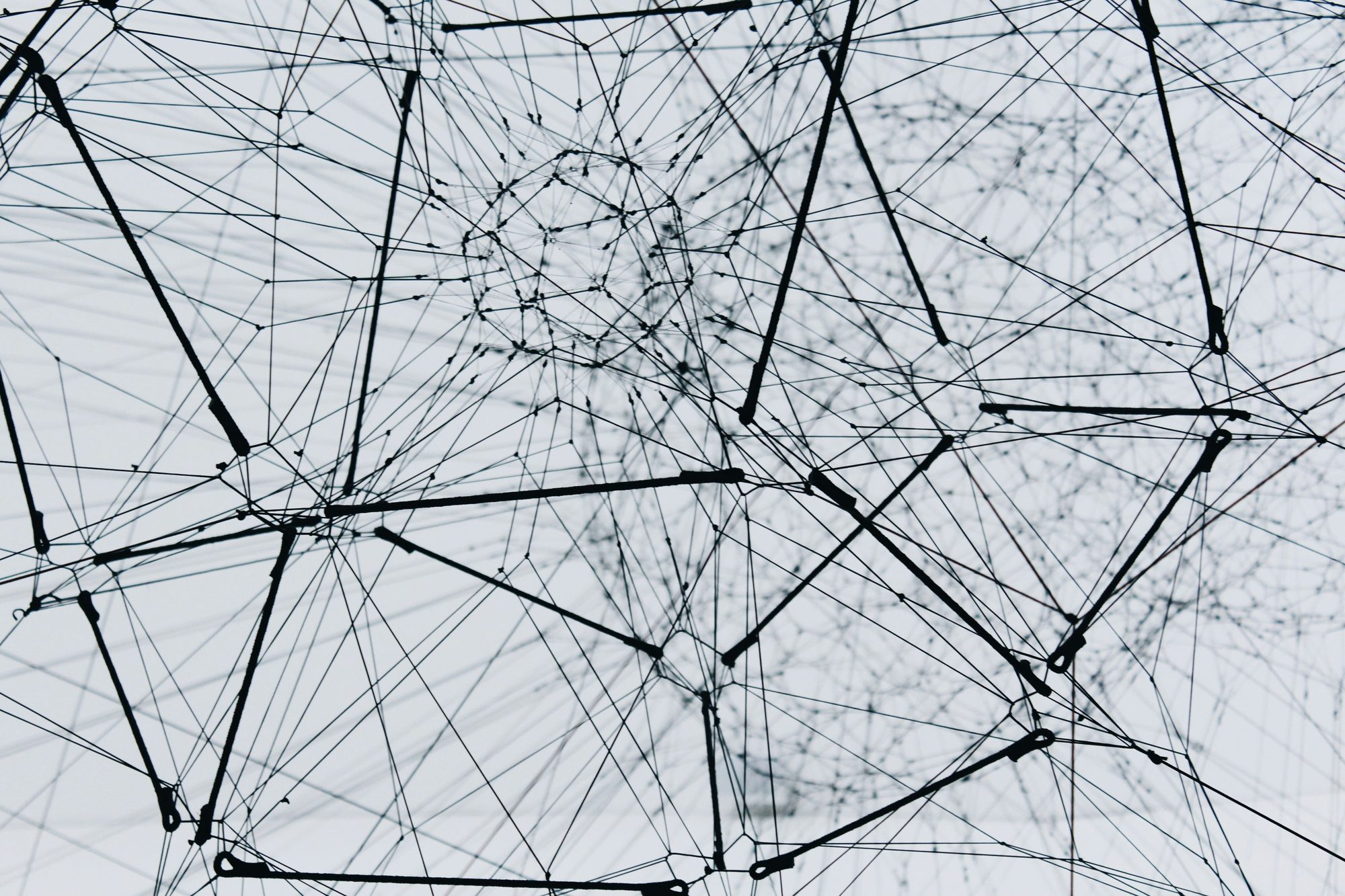 Abstract network of connected nodes and lines against a pale background.