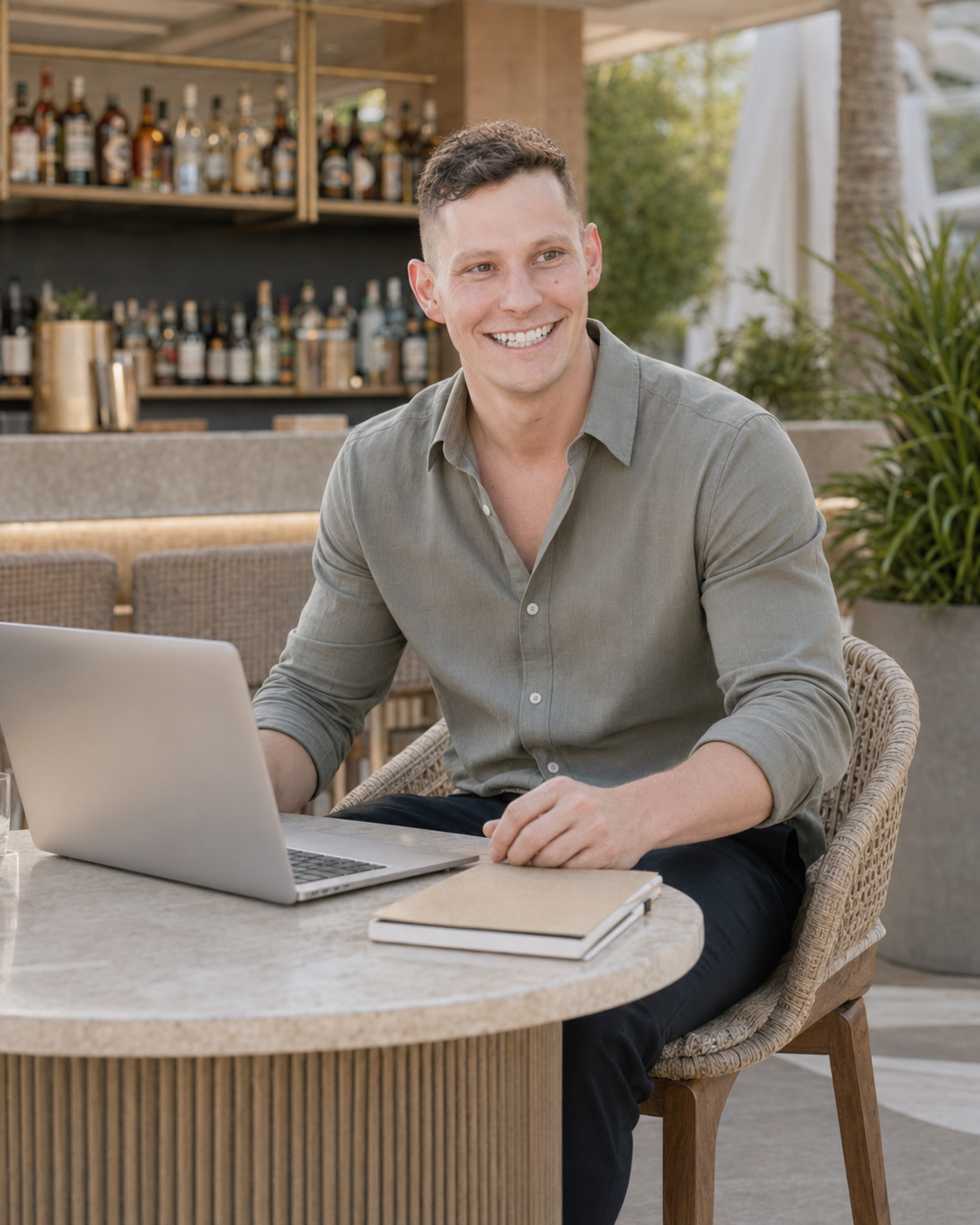 Logan LeBouef working while sitting at a table with a laptop and notebook outdoors.