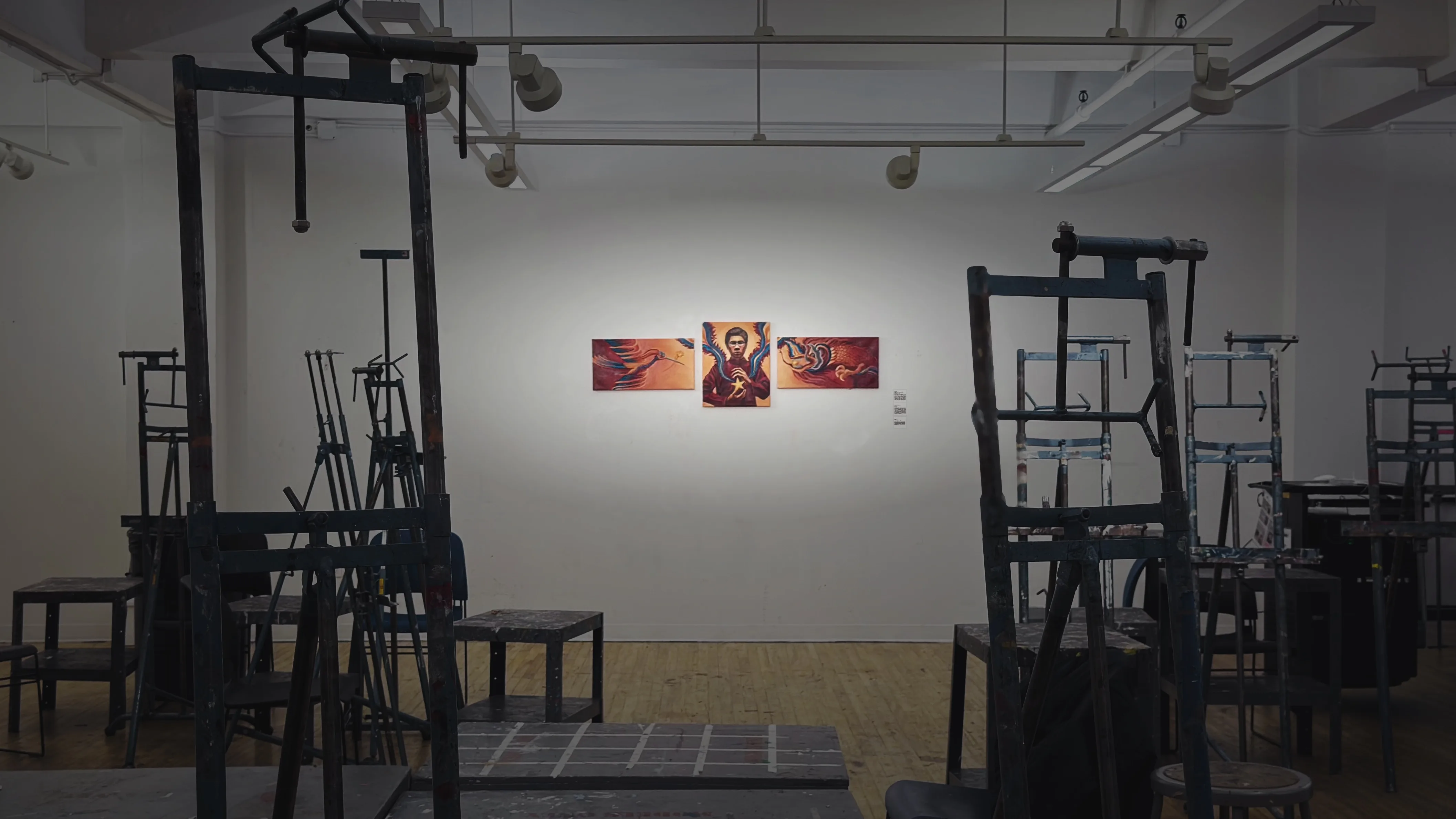 The Vietnamese Spirit triptych hung for a first-year painting critique, seen across a studio room of wooden easels and stools.