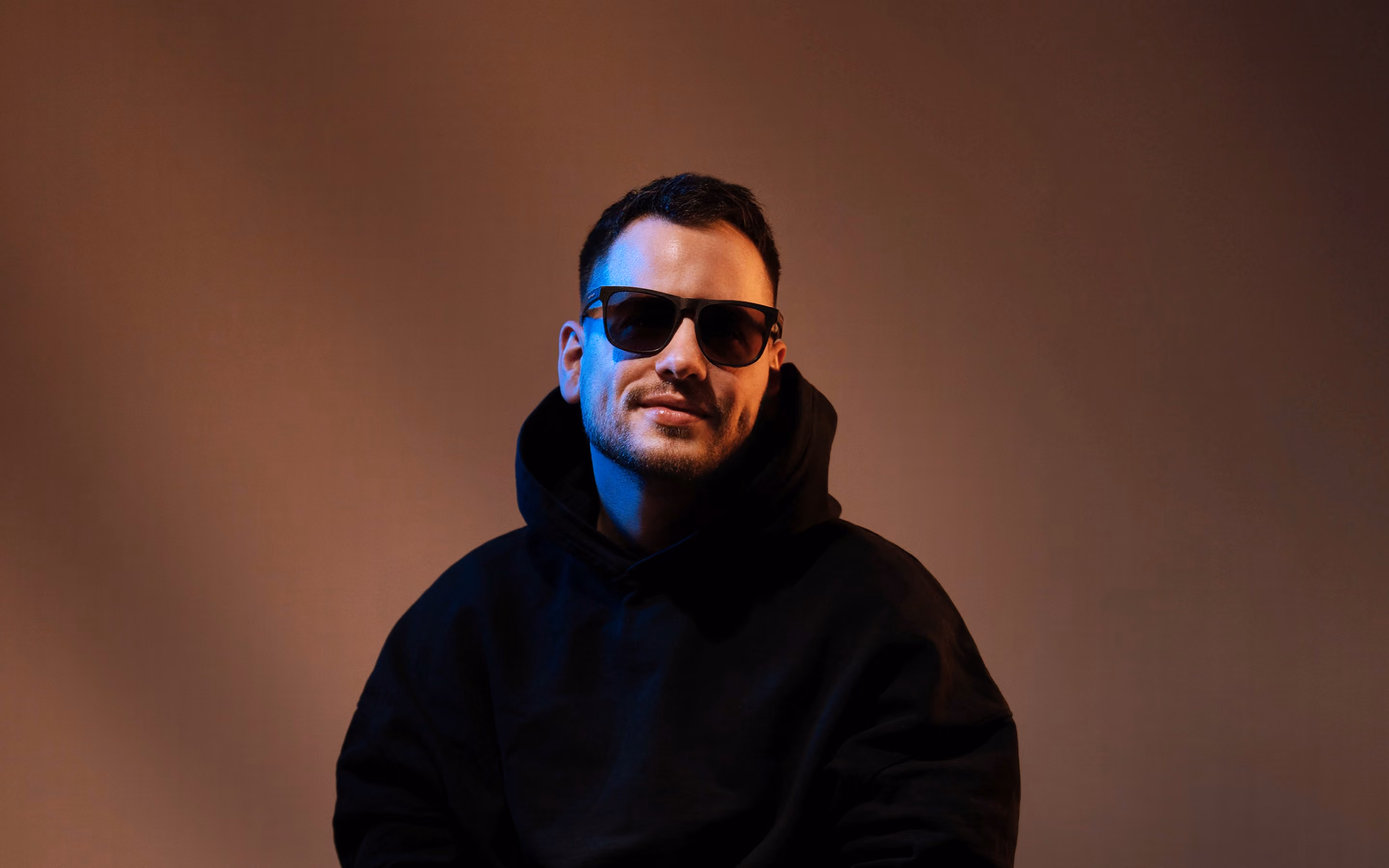 Sascha Thiel, Webflow Freelancer, sitzt auf einem Holzhocker im Fotostudio