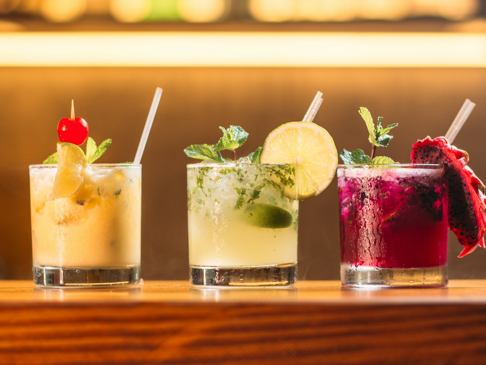 Drie kleurrijke cocktails op een bar