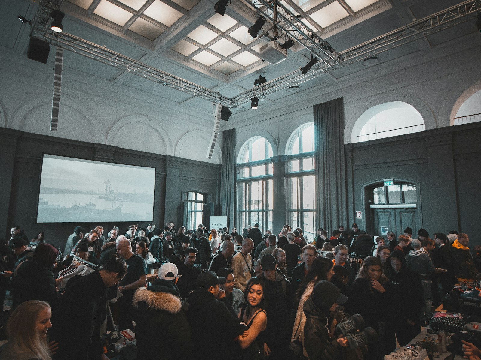 Volle evenementenzaal met publiek voor een groot scherm