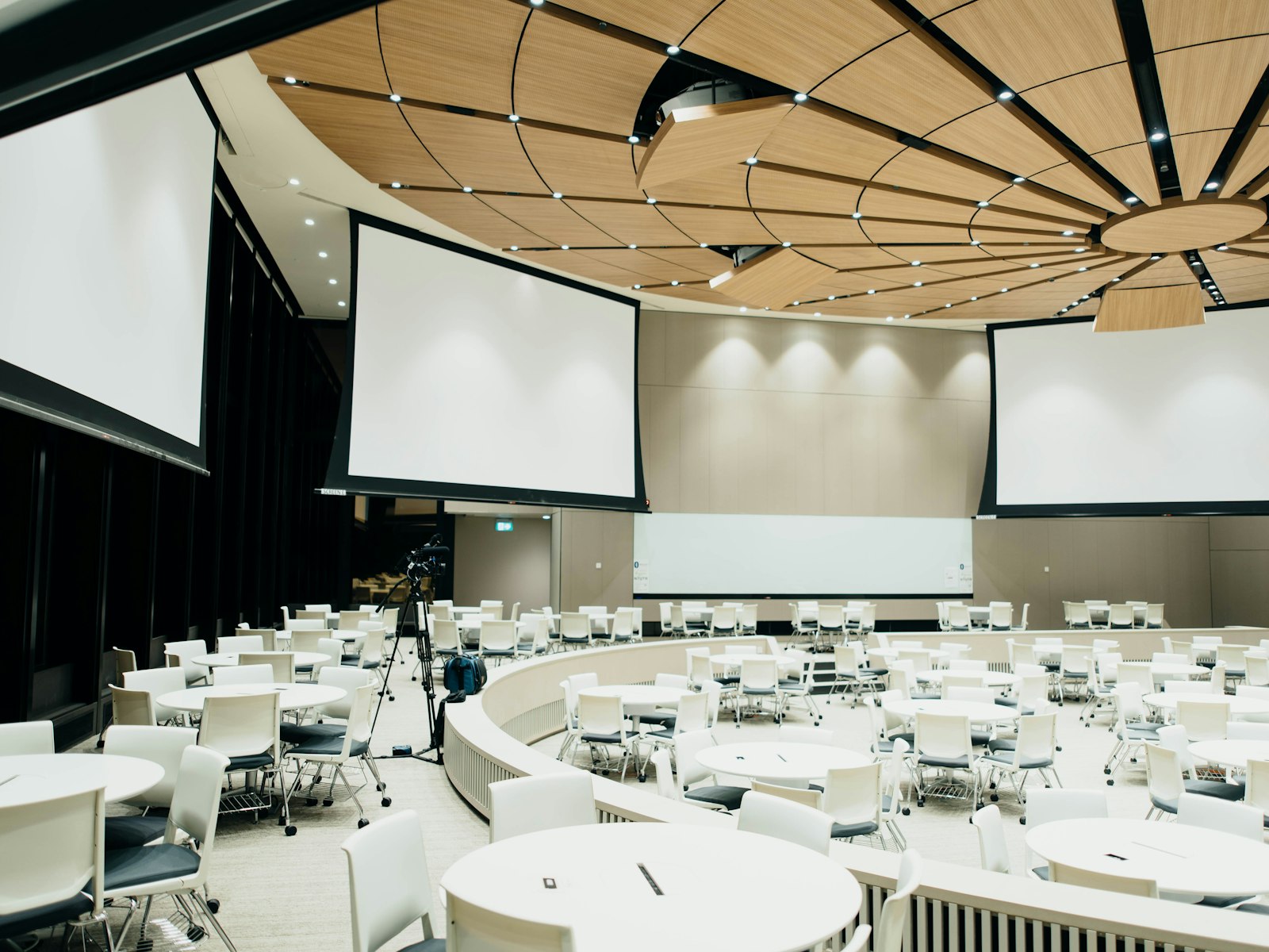 Conferentiezaal met ronde tafels en projectieschermen