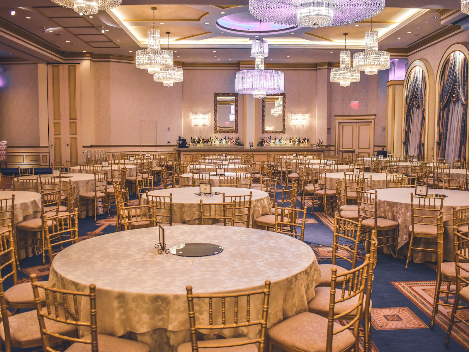 Feestzaal met gedekte ronde tafels en kroonluchters