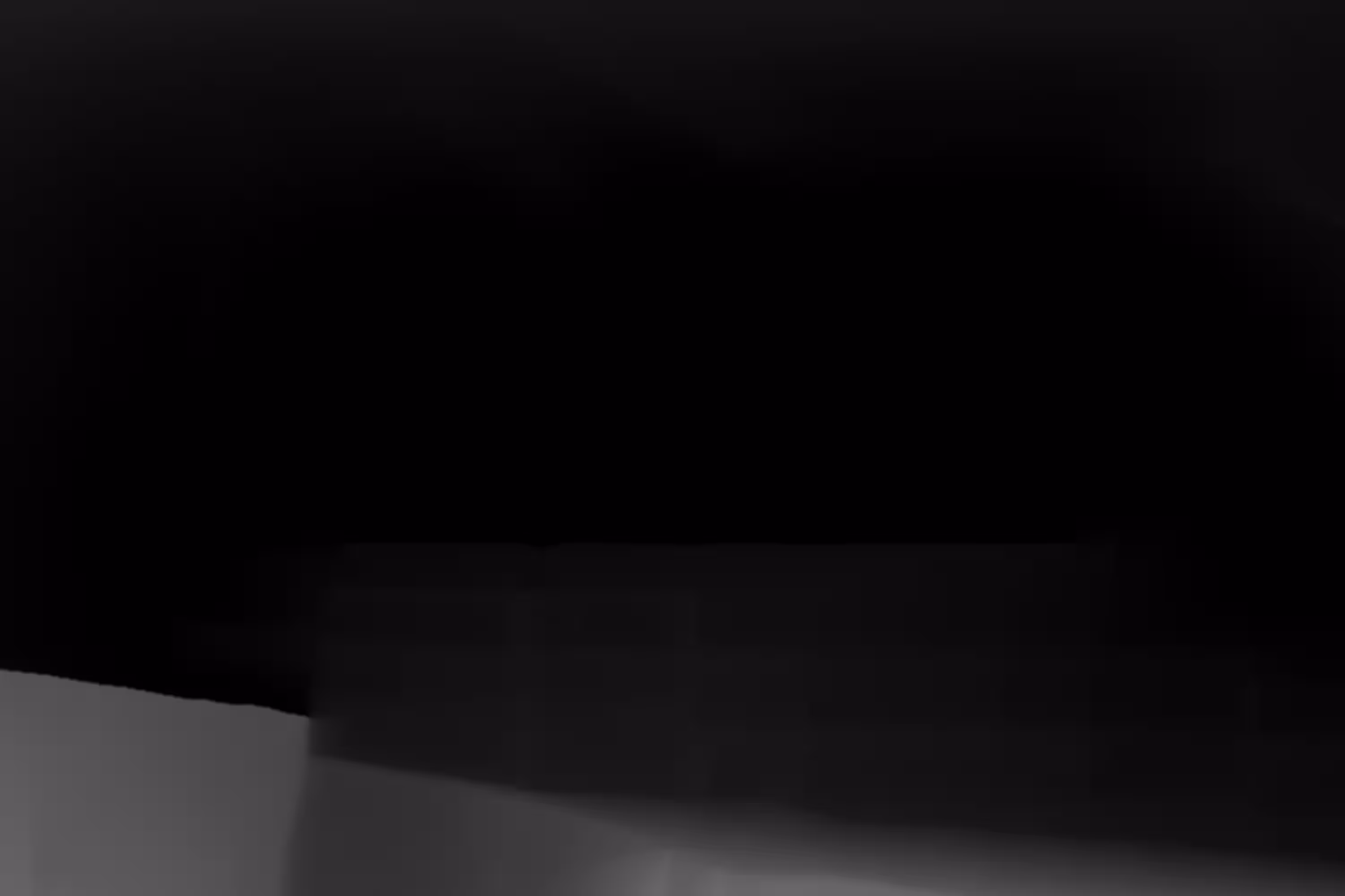 Depth map of a person wearing a helmet holding a steering wheel, grayscale gradient shows distance.