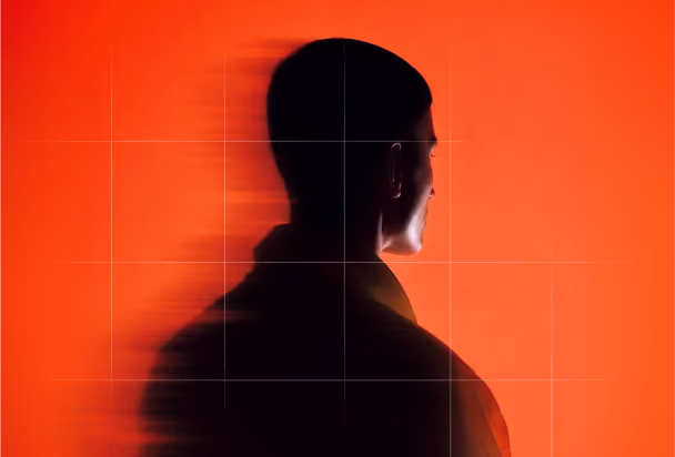 Silhouette of a man in profile facing right against a bright orange background, with a blurred shadow extending to the left.