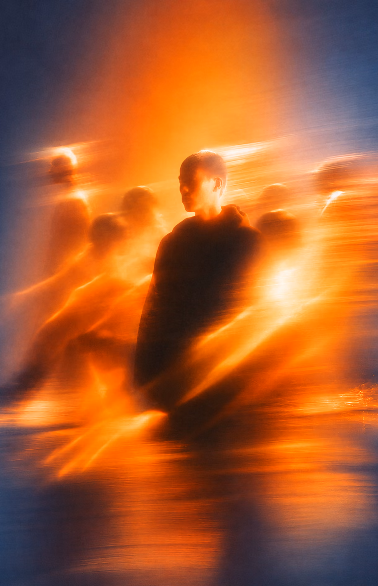 Silhouetted person surrounded by multiple blurred, fiery orange figures on a dark blue background, creating an abstract, glowing effect.