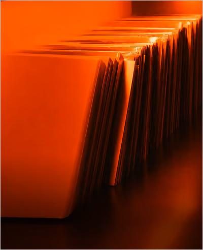 Close-up of an orange-lit filing system with partially open file folders in a row, creating a pattern of vertical edges.