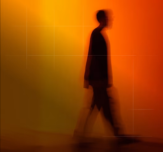 Blurred silhouette of a person walking against a gradient background transitioning from yellow on the left to orange on the right.
