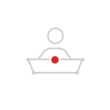 Minimalist icon of a person sitting behind a rectangular desk with a red dot in the center.