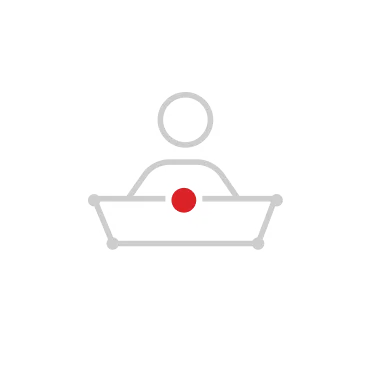 Minimalist icon of a person sitting behind a rectangular desk with a red dot in the center.