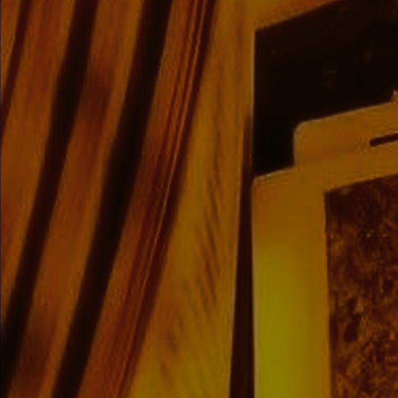 Close-up of a digital tablet with a phone-like notch on top, placed against dark golden-brown curtains with vertical folds.