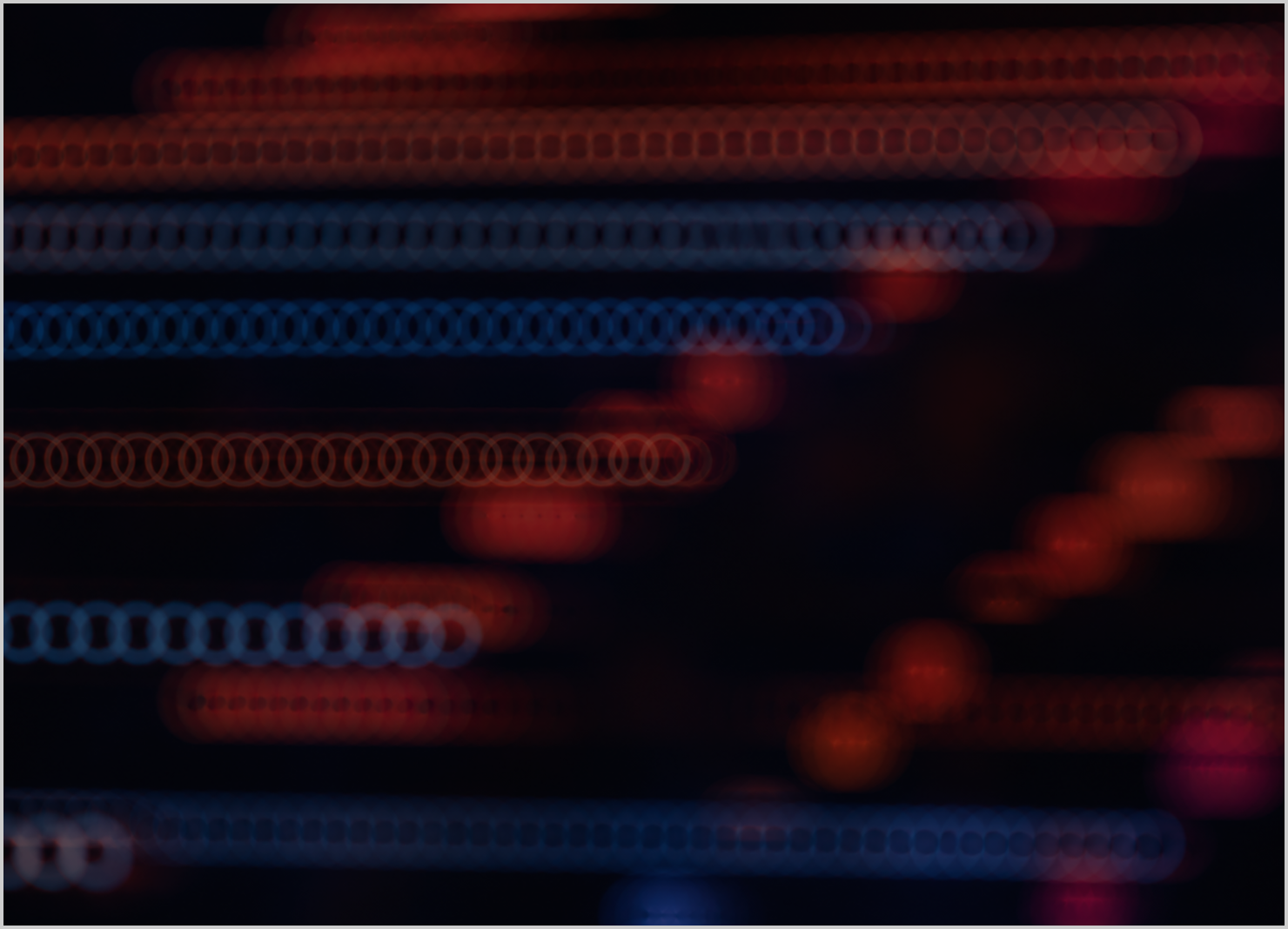 Abstract image showing horizontal rows of circular light patterns in shades of red and blue on a black background.