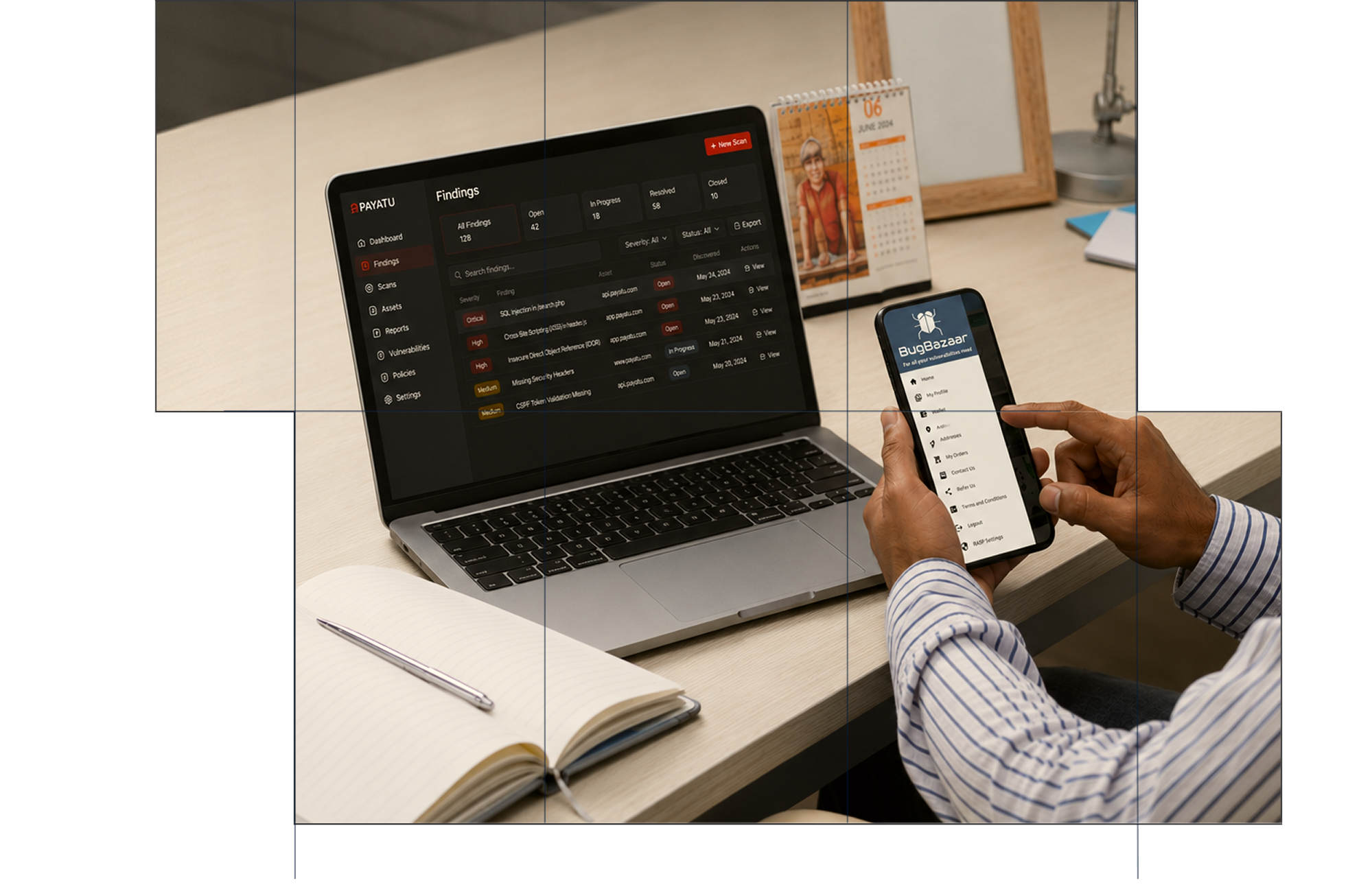 Person holding a smartphone displaying Bugbazaar app menu while sitting at a desk with an open laptop showing a Payatu security findings dashboard. The desk also has a spiral calendar, an open notebook with a pen, and a lamp.