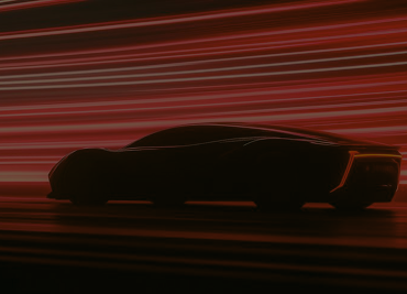 Silhouette of a sleek sports car with red light streaks in the background, suggesting high speed.