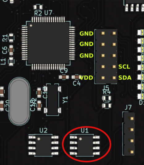 Close-up of an electronic circuit board showing integrated circuits labeled U1 and U2, connectors labeled with GND, VDD, SCL, SDA, and various resistors and capacitors, with U1 highlighted by a red circle.
