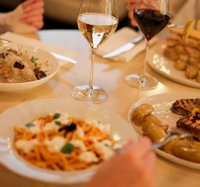 Verres de vin blanc et rouge avec plusieurs plats gourmands sur une table de restaurant.