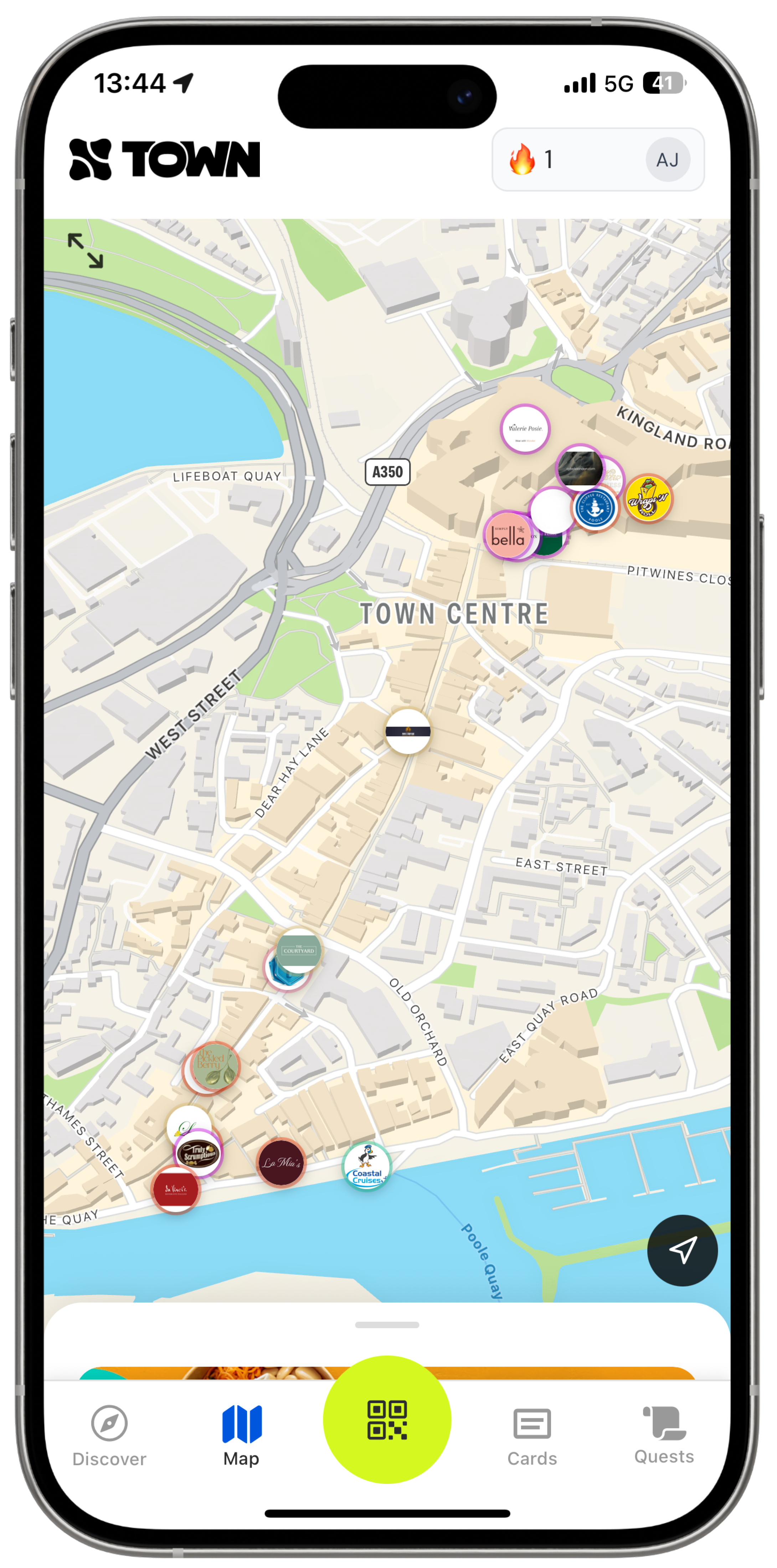 Smartphone screen showing a city map focused on a town centre with various business logos marking locations along streets near a body of water labeled Poole Quay, featuring roads such as West Street, Kingland Road, and Old Orchard. The app header displays the TOWN logo and user icons, and the bottom menu has options Discover, Map, a highlighted QR code button, Cards, and Quests.