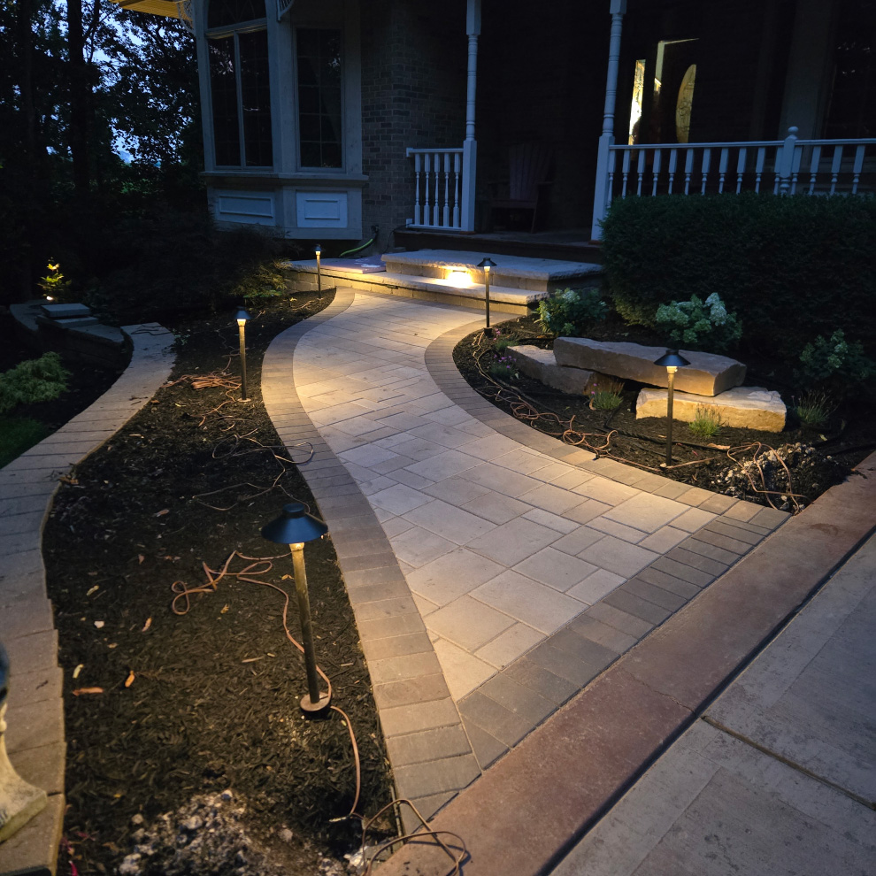 Curved paver front walkway at the Richards Residence lit at dusk by low landscape path lights.