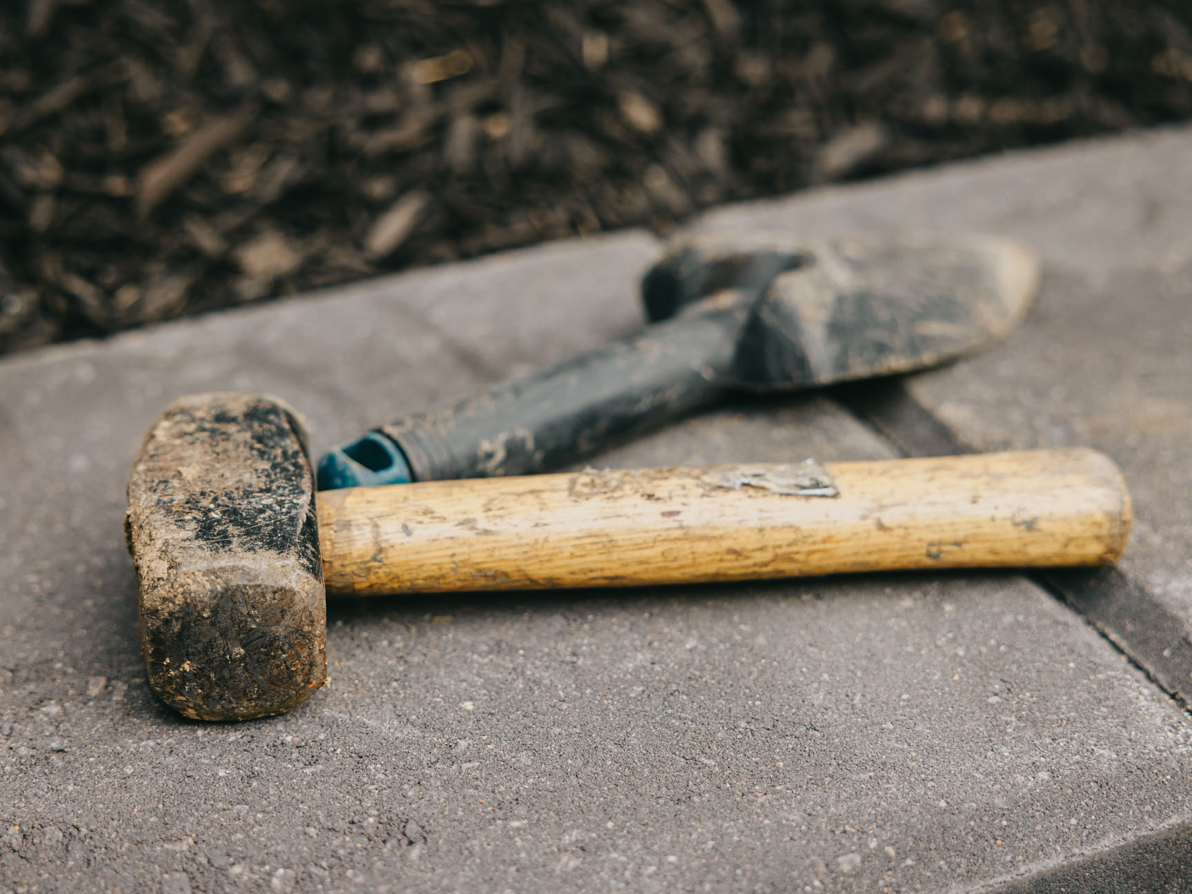 Hammer and trowel resting on freshly laid paver stones during a hardscape build.