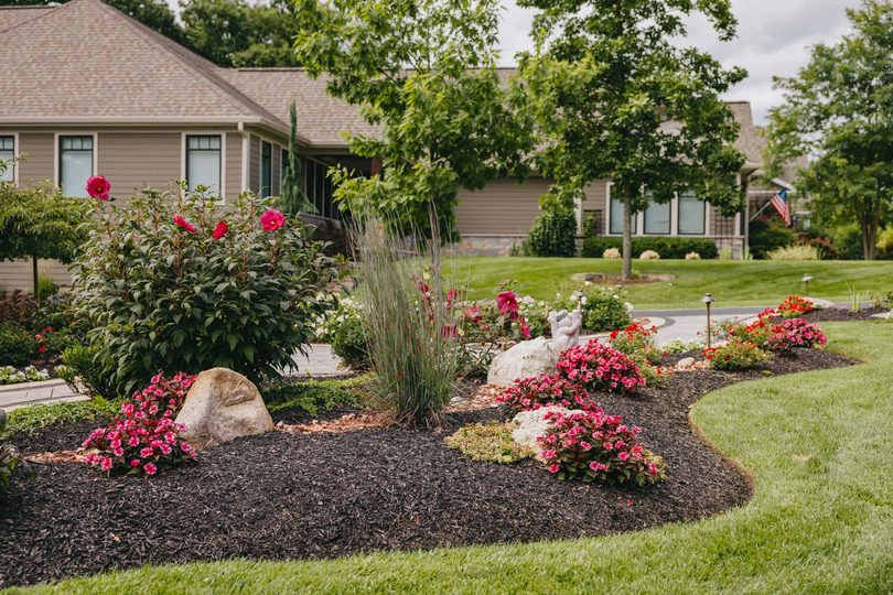 Manicured front yard with vibrant flower beds and clean trench edging.