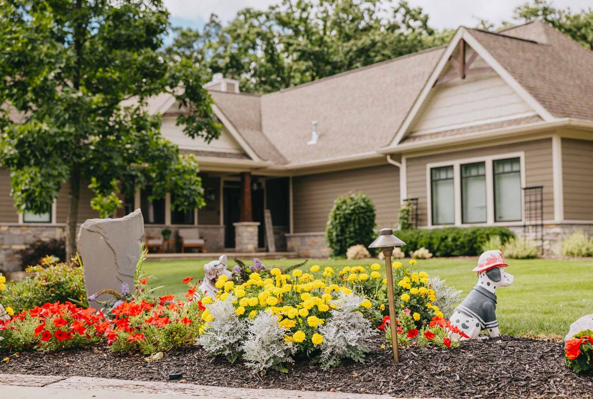 Front yard flower bed with yellow marigolds, red petunias, and decorative lighting.