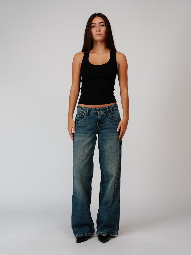 Full length from the front, black vest and dark jeans, arms by her sides