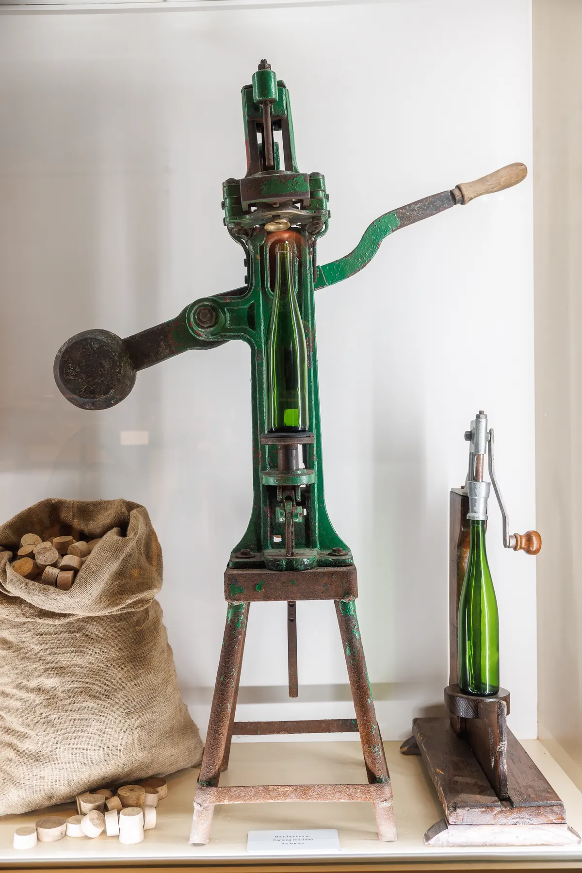 Antique green cast-iron bottle corking machine, with a bag of corks