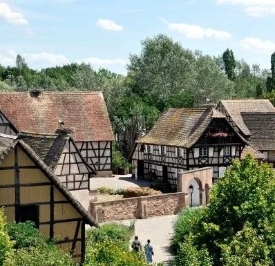 Maisons à colombages traditionnelles et jardins de l’Écomusée d’Alsace sous un ciel d’été