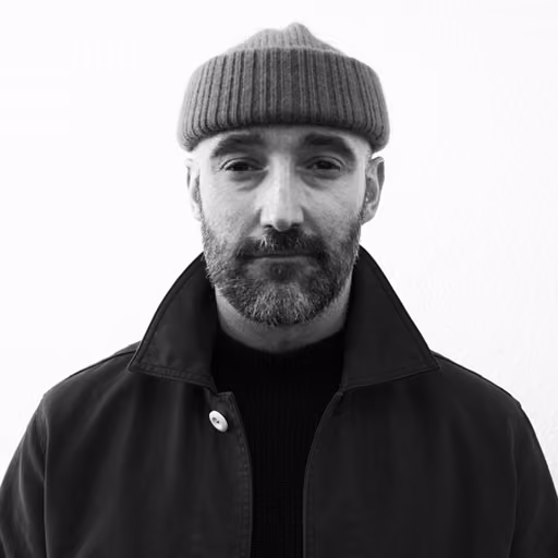 Black and white portrait of a man with glasses, short hair, a mustache, and a beard.