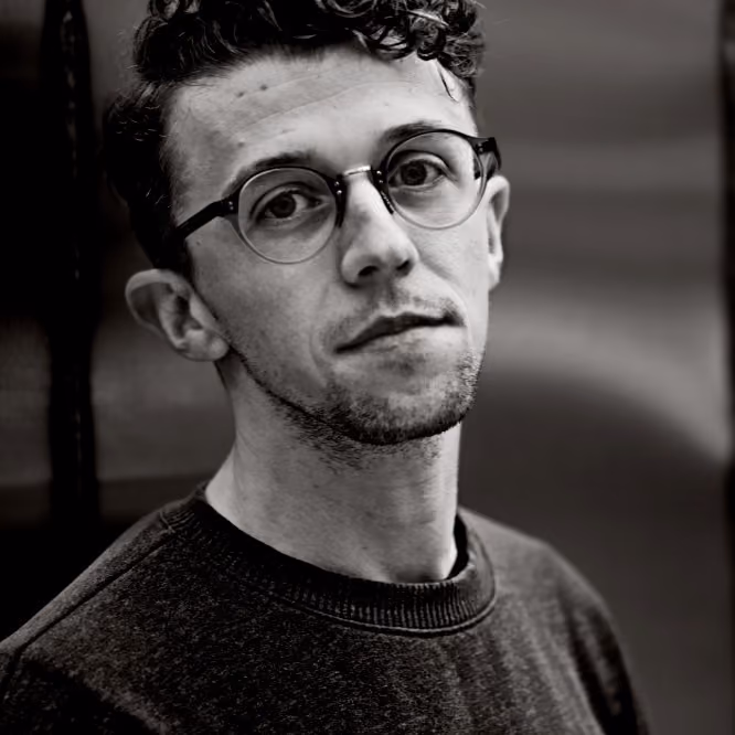 Black and white portrait of a man with glasses, short hair, a mustache, and a beard.