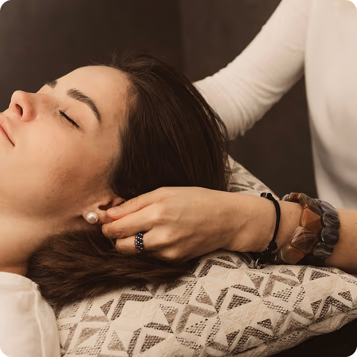 Person with closed eyes receiving a gentle ear massage from another person.
