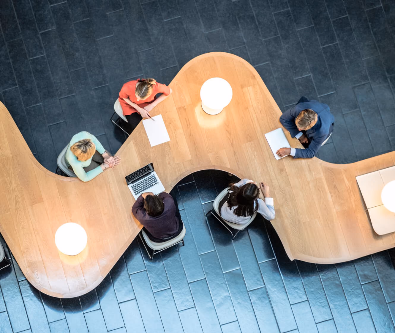 Overhead view of colleagues working at a curved shared desk