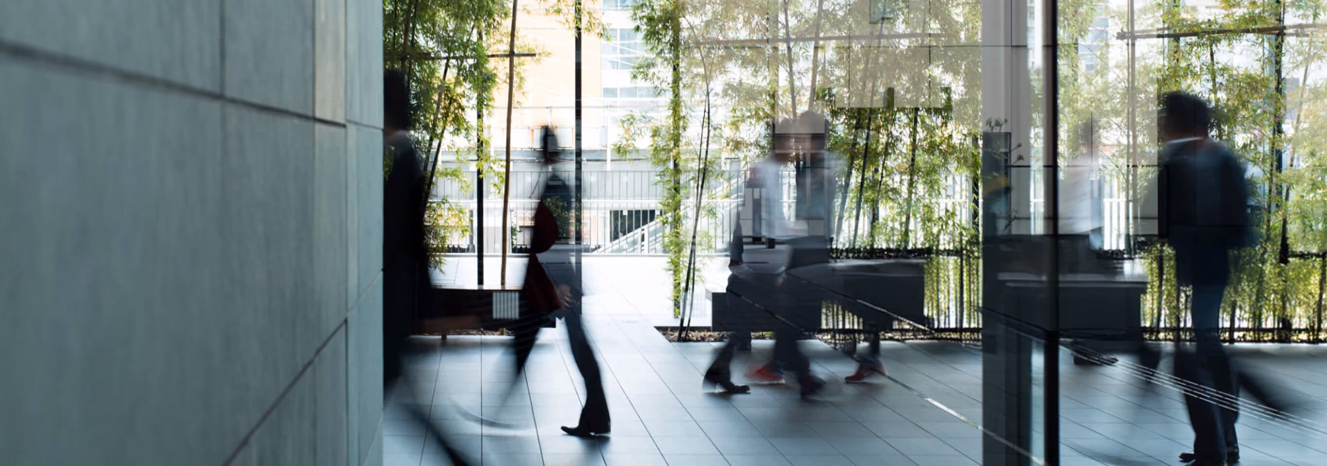People walking through a glass-walled office lobby