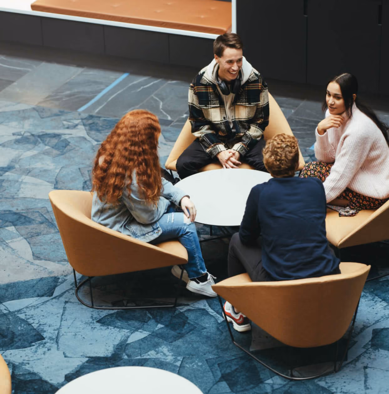 Colleagues talking in armchairs around a low table in an office lounge