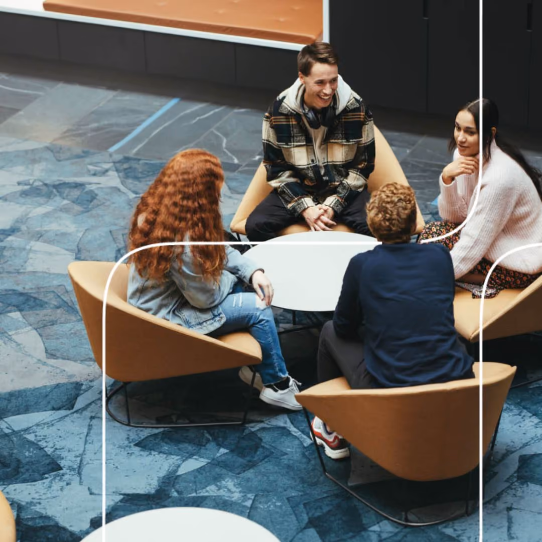 Colleagues talking in armchairs around a low table in an office lounge