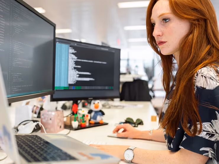 Developer working at a desk with code on two monitors