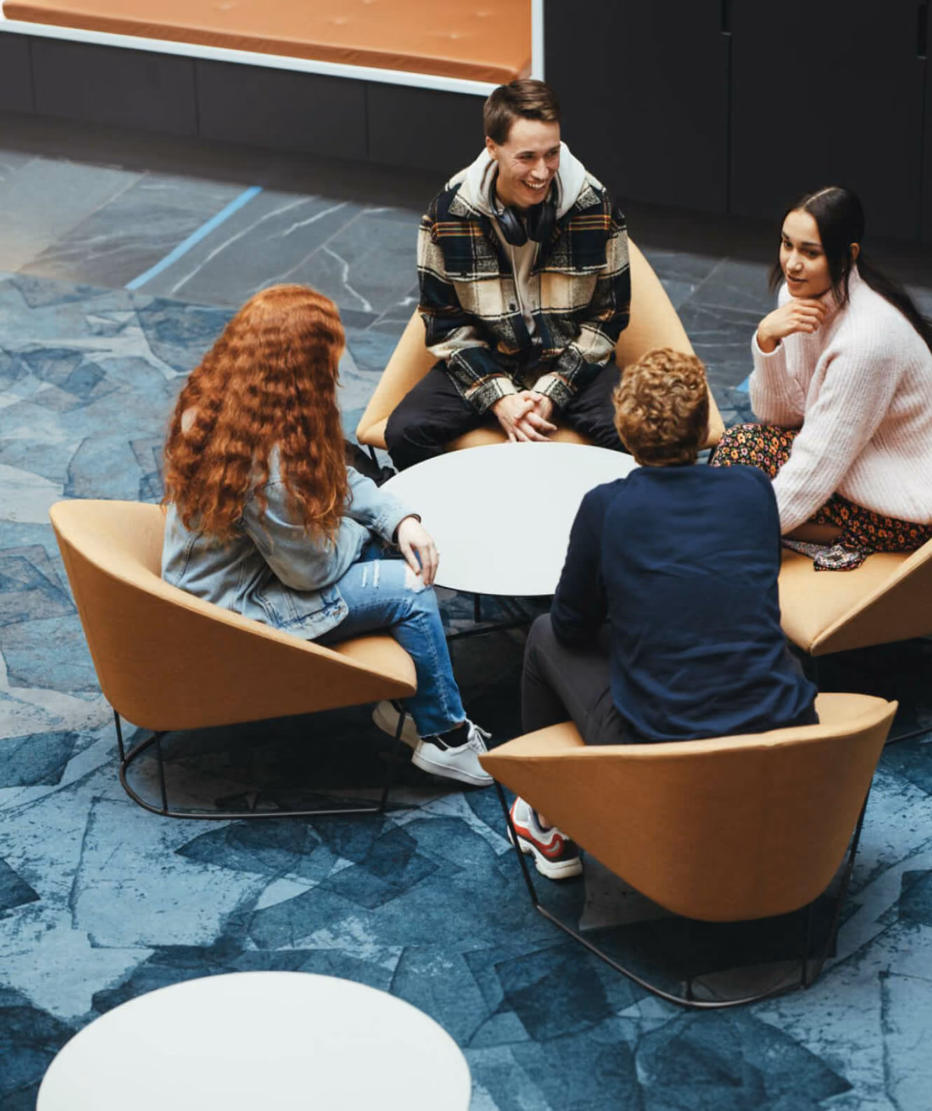 Colleagues talking in armchairs around a low table in an office lounge