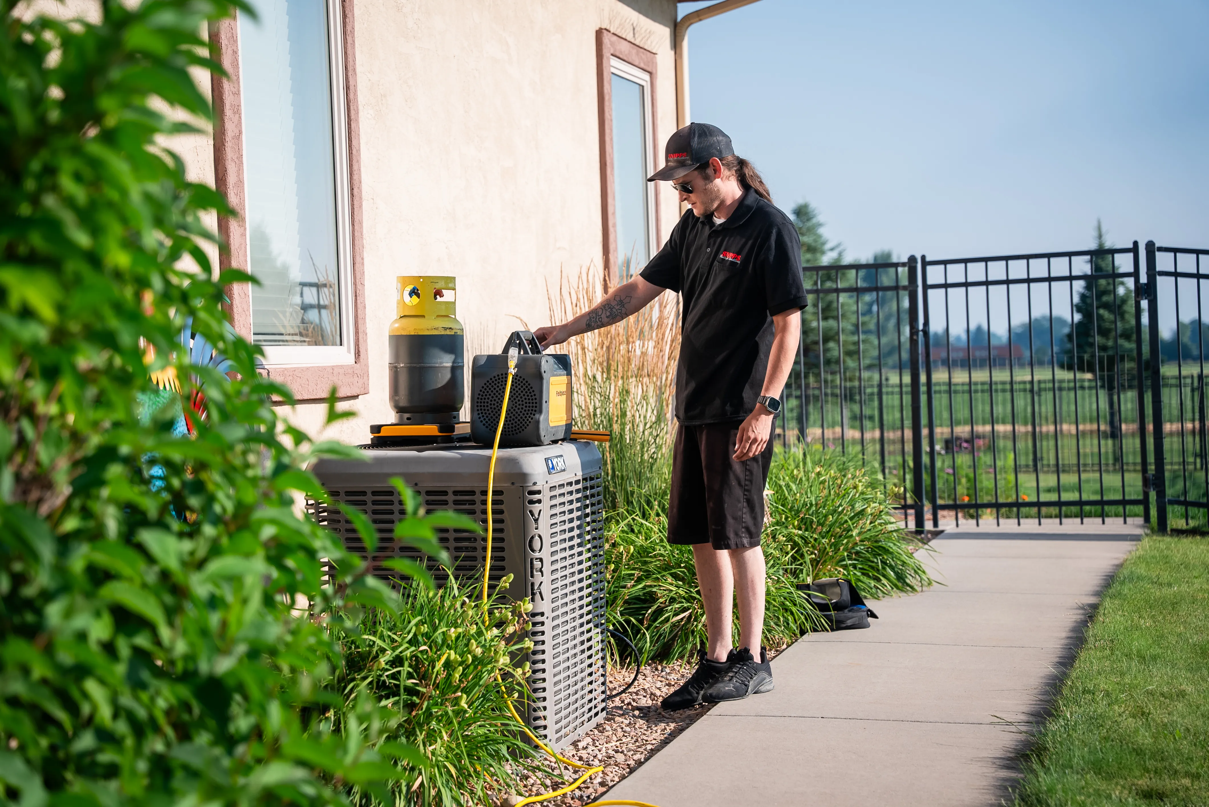 Snipps technician servicing an outdoor heat pump unit at a Colorado home