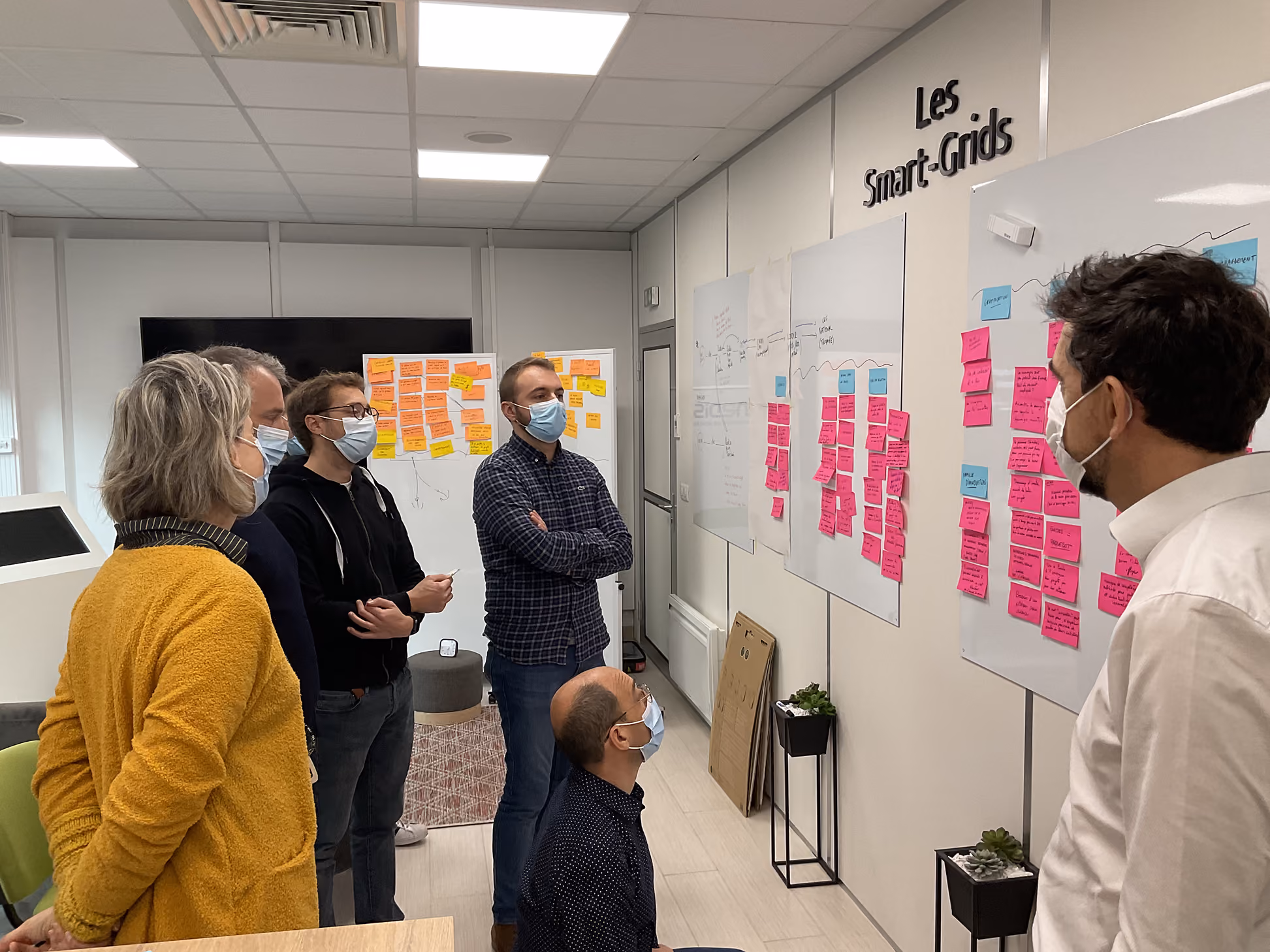Participants masqués observant un mur de post-it lors d'un atelier