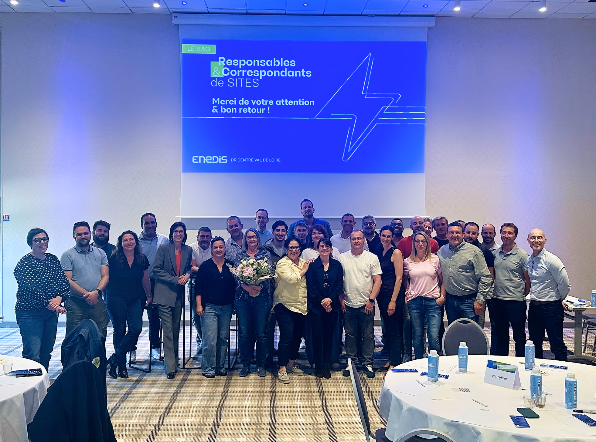 Photo de groupe dans une salle de séminaire Enedis, devant un écran de présentation