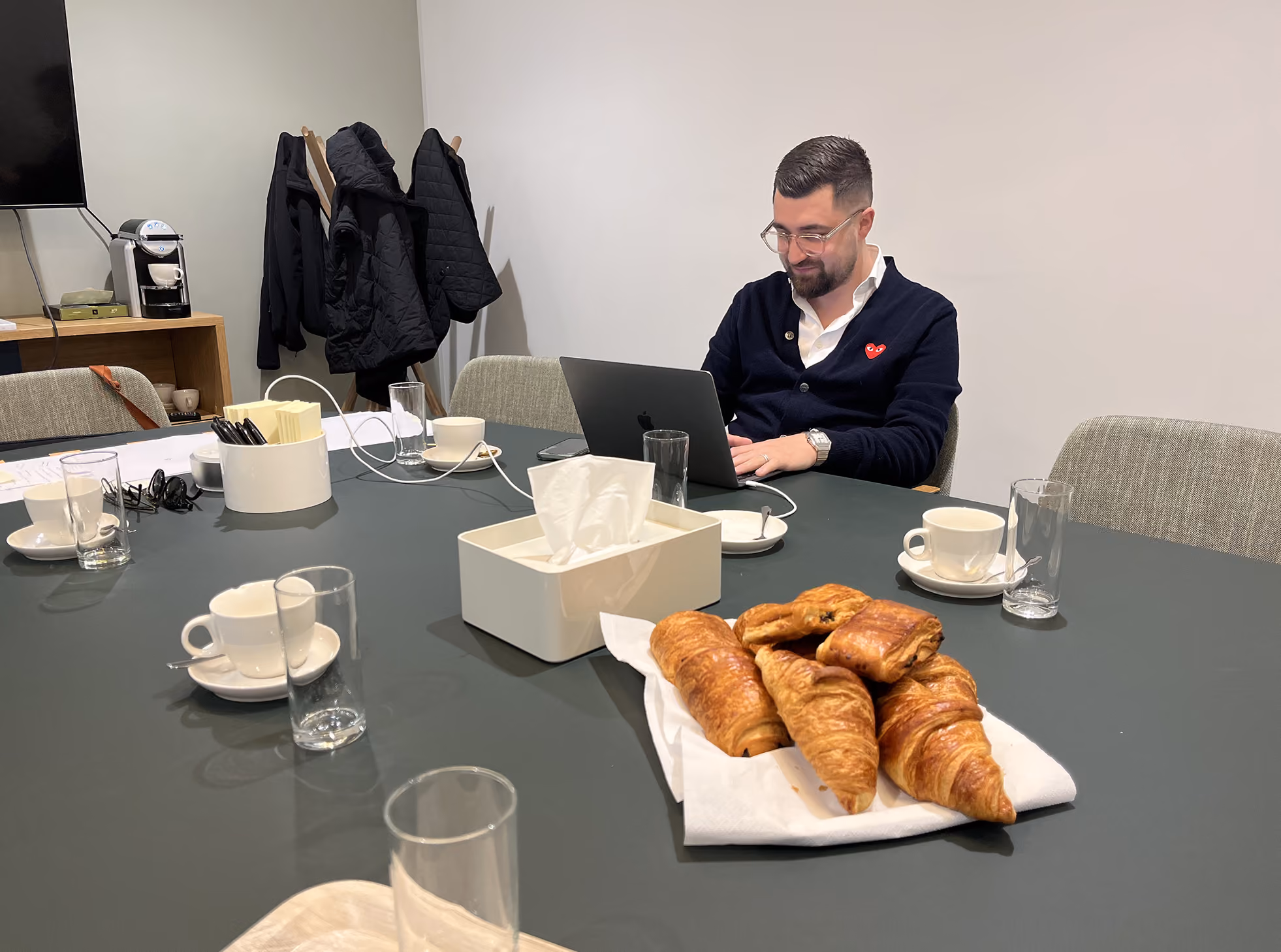 Homme travaillant sur un ordinateur portable, des croissants sur la table