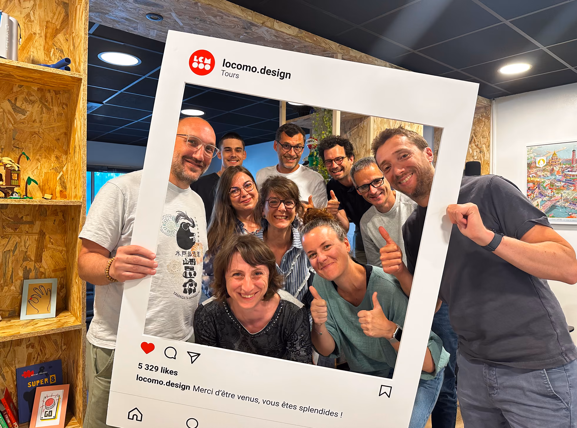 Groupe souriant, pouces levés, derrière un cadre Instagram « locomo.design »