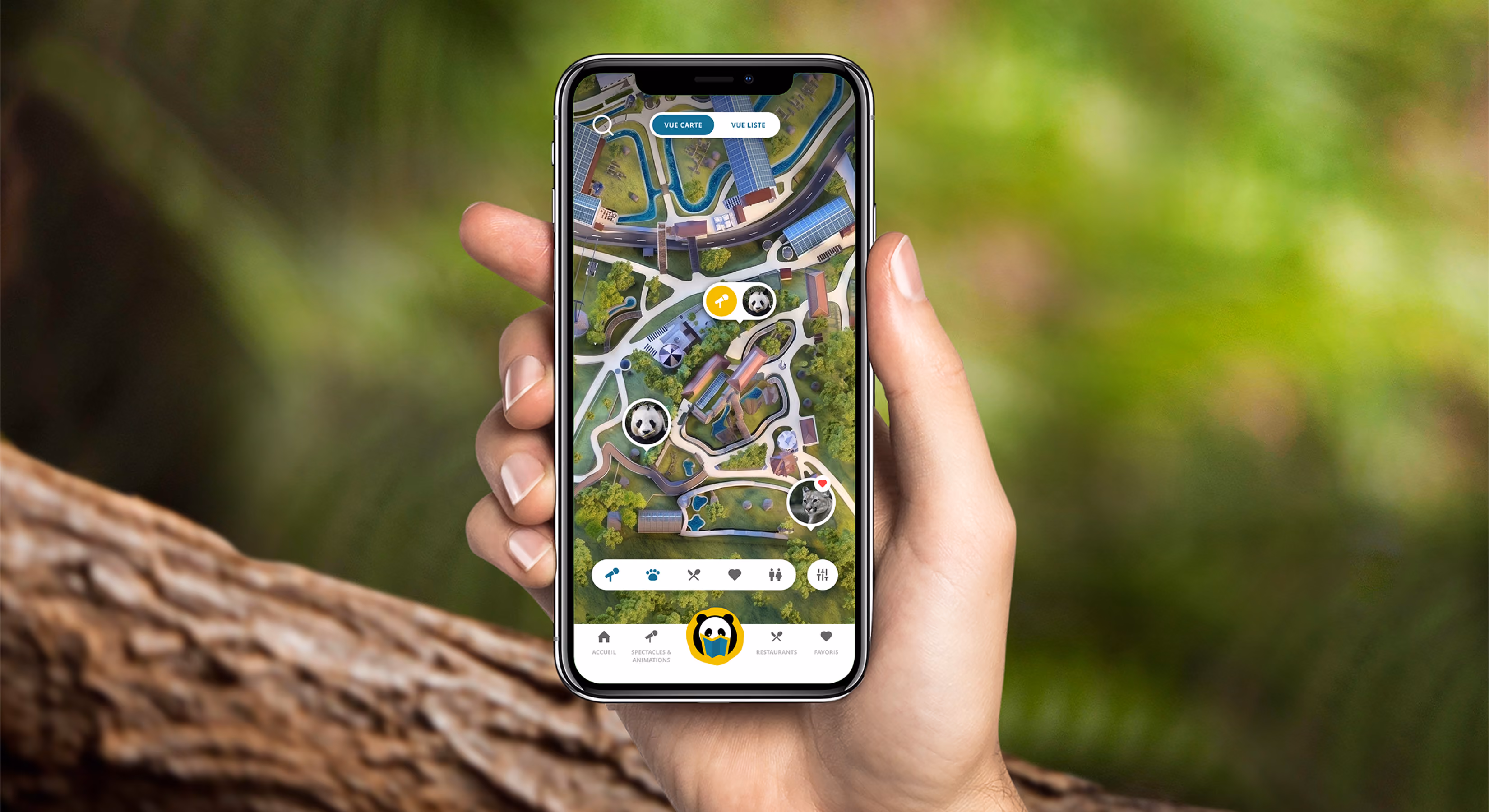 Main tenant un smartphone affichant le plan interactif du ZooParc, sur fond de feuillage