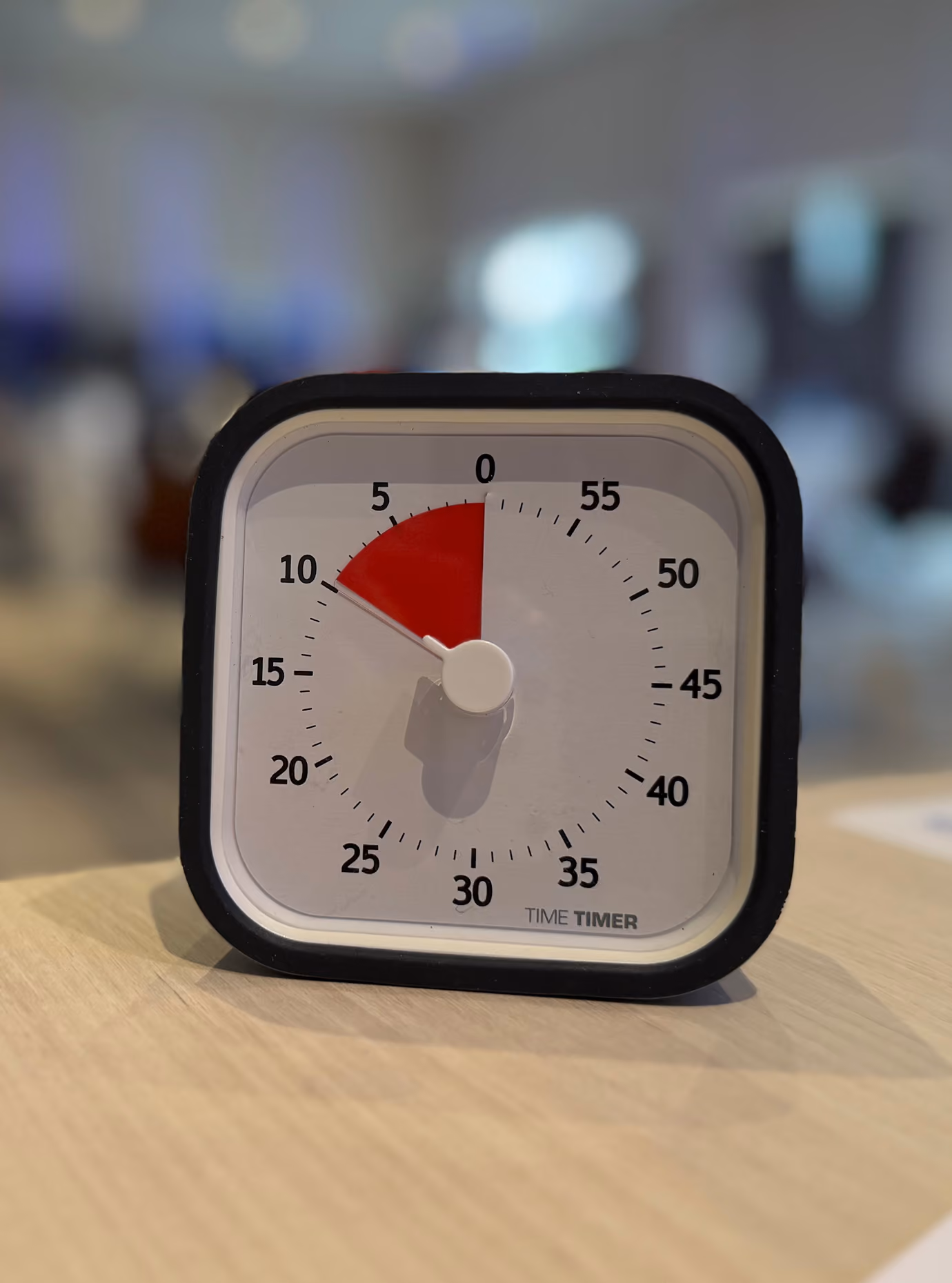 Chronomètre Time Timer posé sur une table, l'aiguille rouge sur cinq minutes