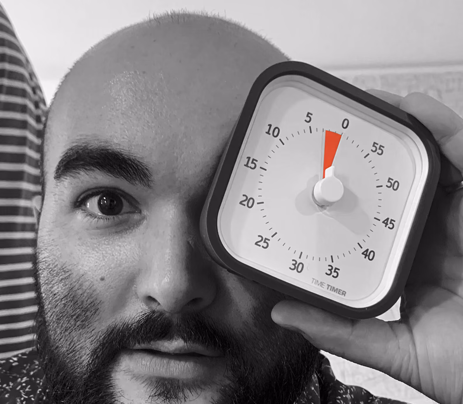 Portrait en noir et blanc d'un homme tenant un minuteur devant son œil