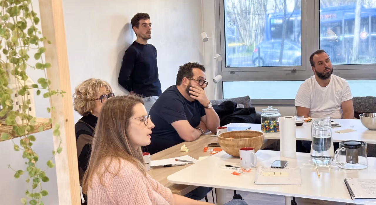 Participants d'un atelier assis autour d'une table, certains prenant des notes